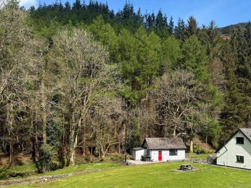 a white house with a red door in a field at Cuckoo Cabin, Tyn Y Cwm in Scyborycoed