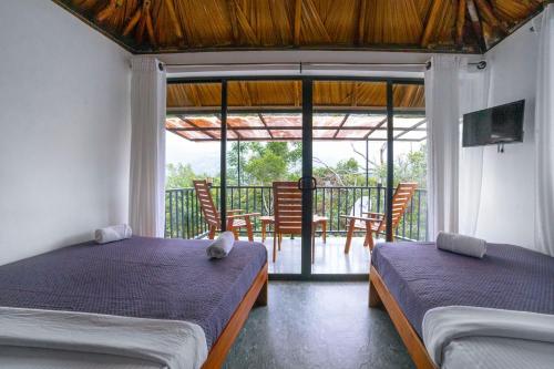 two beds in a room with a balcony at Ollie resort in Ella