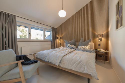 a bedroom with a bed and a chair and a window at Ferienhaus Daheim in Sankt Peter