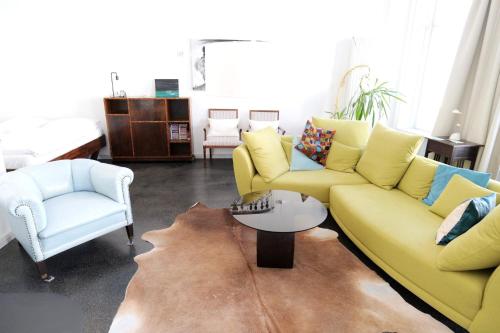 a living room with a yellow couch and two chairs at Zuhause am Boulevard - ABC40 in Wismar