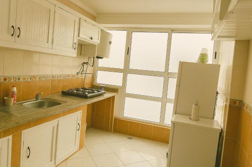 a kitchen with a white refrigerator and a window at Miss ALIA Aéroport in Tangier