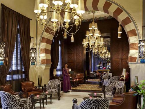 eine Frau steht in einem Raum mit Stühlen und einem Kronleuchter in der Unterkunft Sofitel Legend Old Cataract in Assuan