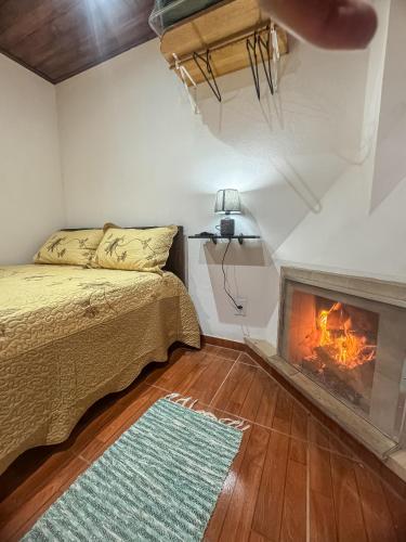 a bedroom with a bed and a fireplace at Morada do Sabiá - chalé 1 in Resende