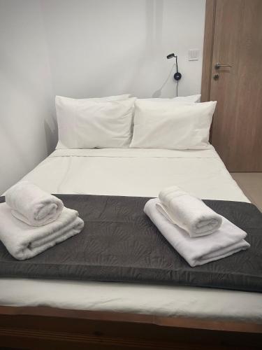 a bed with white sheets and two towels on it at MINAS CENTRAL apartments in Heraklio