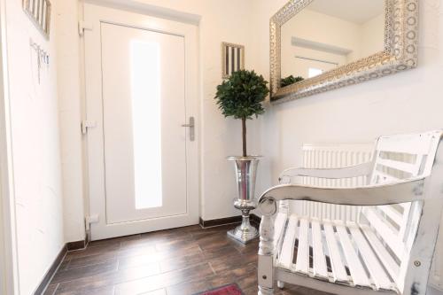 a white rocking chair in a hallway with a mirror at Ferienhaus "Hus Oetti" in Ostseebad Sellin