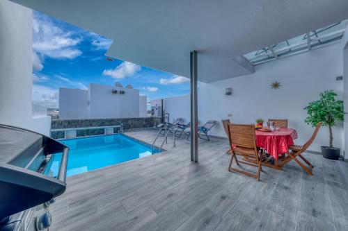 a balcony with a table and chairs and a pool at Villa Mariña- Heated pool in Playa Blanca
