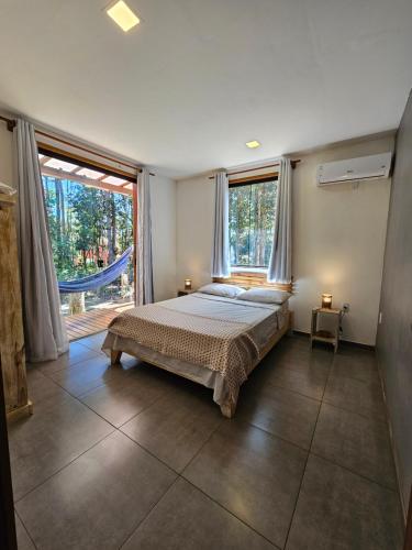 een slaapkamer met een bed en een groot raam bij Maison CATU in Itacaré
