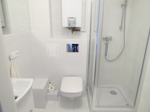 a white bathroom with a shower and a toilet at Rynek Staromiejski Apartment in Koszalin