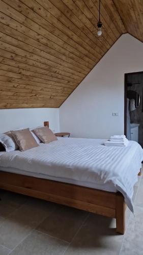 a large bed in a room with a wooden ceiling at EDANT HOUSE in Bumbesti Pitic