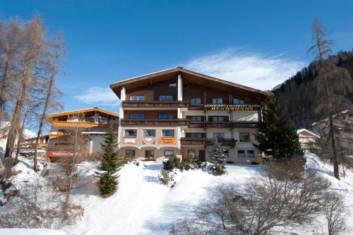 a large building on a snow covered slope with trees at Apartment Bergsonne in Samnaun