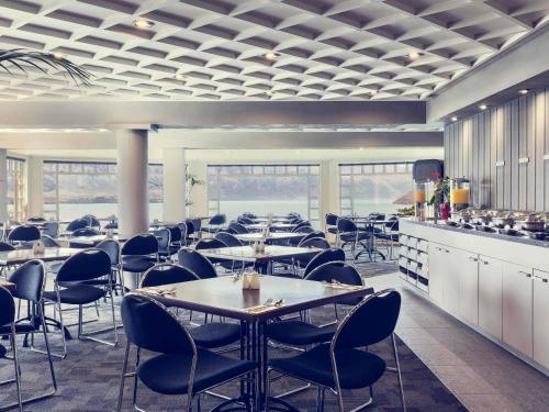 a restaurant with tables and chairs in a room at Mercure Queenstown Resort in Queenstown