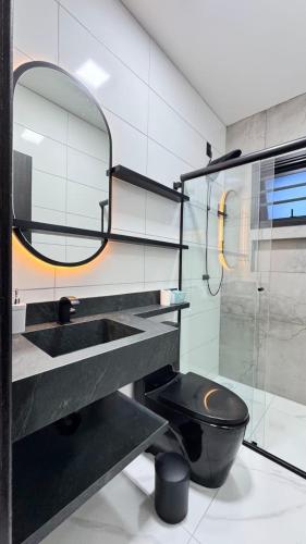 a bathroom with a black toilet and a mirror at Mare Mansa Residence in Florianópolis