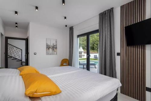 een slaapkamer met een bed met gele kussens en een raam bij Luxury Sea View Villa DIJANA with Infinity Pool & Jacuzzi Near Rijeka in Kostrena