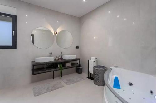 een badkamer met 2 wastafels, een bad en spiegels bij Luxury Sea View Villa DIJANA with Infinity Pool & Jacuzzi Near Rijeka in Kostrena