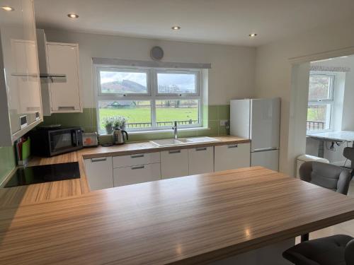 a kitchen with a wooden table and a refrigerator at Swn yr Coed in Sennybridge