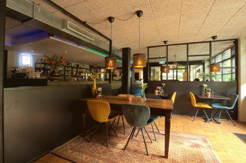 a restaurant with a wooden table and yellow chairs at Recreatiebungalow Lochem in Lochem
