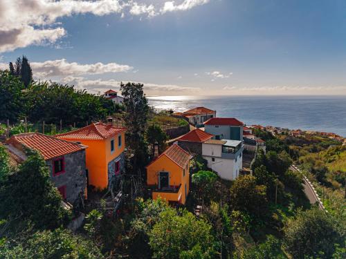 a village on a hill with the ocean in the background at Madeira-Meerblick-Haus in Estreito da Calheta