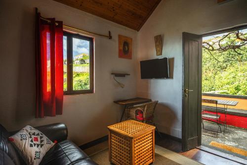 a living room with a couch and a tv and a window at Madeira-Meerblick-Haus in Estreito da Calheta