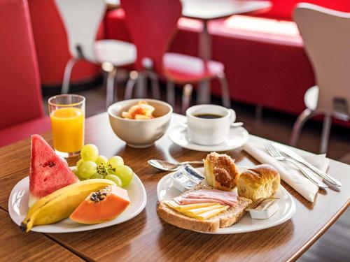 a table with two plates of breakfast foods and orange juice at ibis Sao Jose dos Campos Dutra in São José dos Campos
