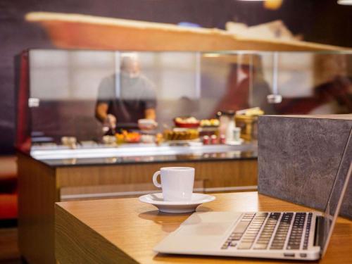 a laptop computer sitting on a table with a cup of coffee at ibis Sao Jose dos Campos Dutra in São José dos Campos
