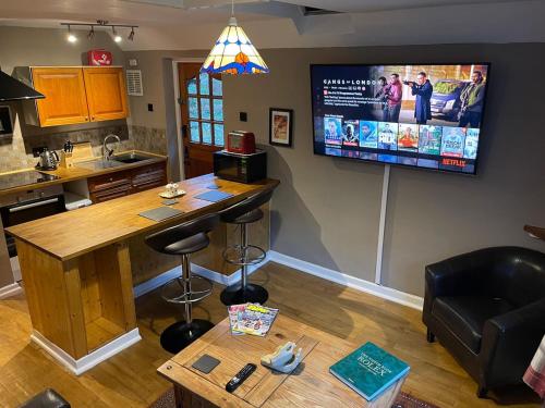 a kitchen with a bar and a tv on the wall at Bear Cottage in Scyborycoed