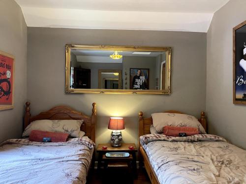 a bedroom with two beds and a mirror at Bear Cottage in Scyborycoed