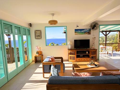 a living room with a couch and a tv at Espace Harmonie Deshaies - Vue Mer & Piscine Panoramique in Deshaies