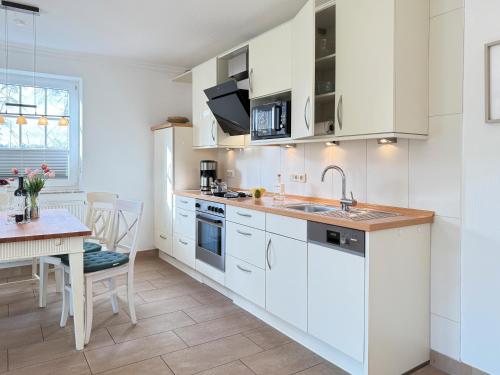 a kitchen with white cabinets and a dining table at Öresundhus 2 in Prerow