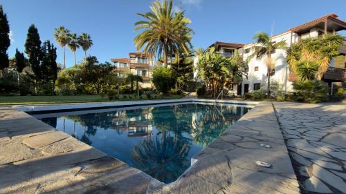 a swimming pool in front of a house with palm trees at Almabella in Breña Baja