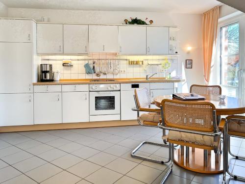 a kitchen with white cabinets and a table and chairs at Windwatt 4 in Zingst