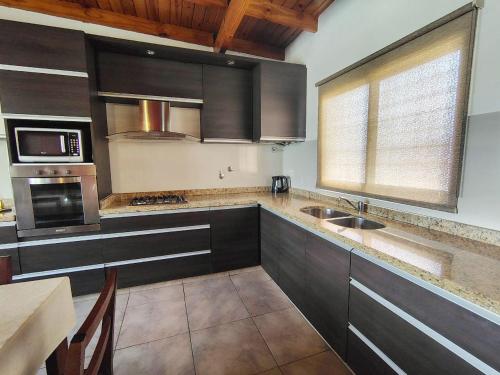 a kitchen with black cabinets and a sink and a window at Depto Viamonte PlantaAlta, 2Dorm, Terraza, Cochera in Cordoba