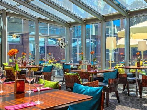 een restaurant met tafels, stoelen en ramen bij Mercure Gdańsk Stare Miasto in Gdańsk