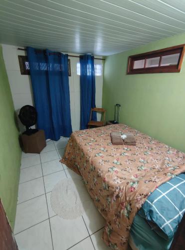 a bedroom with a bed and blue curtains at Jully's house in Arraial do Cabo
