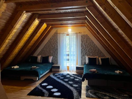 a attic room with two beds and a window at Cozy Cottage Vlašić in Vlasic