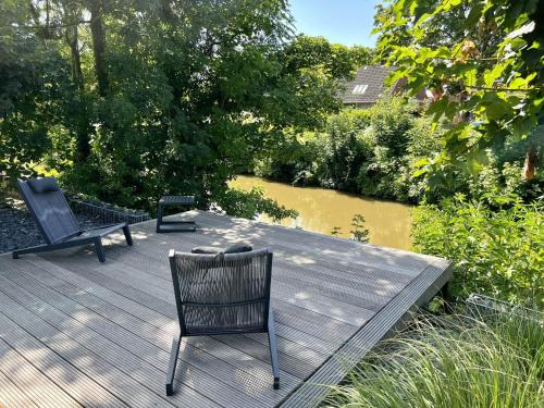 twee stoelen op een houten terras naast een rivier bij Haus am Siel 02 in Greetsiel