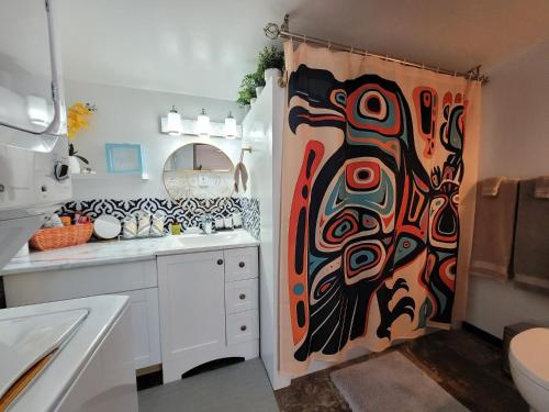 a bathroom with a shower curtain with a painting on it at Nesting Ravens cottage in Nanaimo