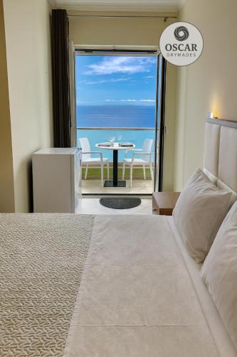 a bedroom with a bed and a view of the ocean at Oscar’s Apartments Drymades in Dhërmi