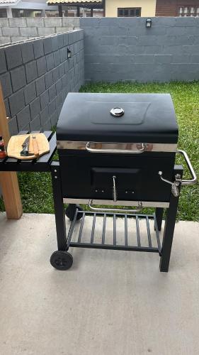 a grill sitting on a stand in a yard at Cabana Maciambu casa de praia Palhoça SC in Palhoça