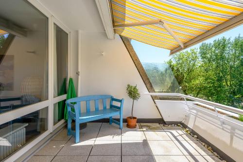 een blauwe stoel op een balkon met een raam bij Strandläufer in Schilksee