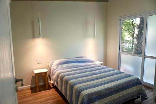 a bedroom with a bed with a striped blanket and a window at Blanco Jazmines in Concepción del Uruguay