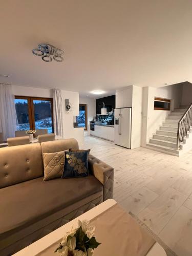 a living room with a couch and a kitchen at Glamoon Mountain Apartment with Jacuzzi and Sauna, Nowy Targ in Nowy Targ