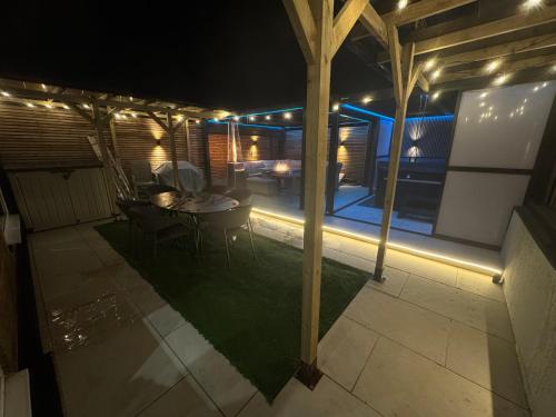 a patio with a table and chairs at night at 5 Bed Town House With Additional Luxury Hot Tub And Within City Centre And Sleeps Up To 11 With Sky And Netflix in Birmingham