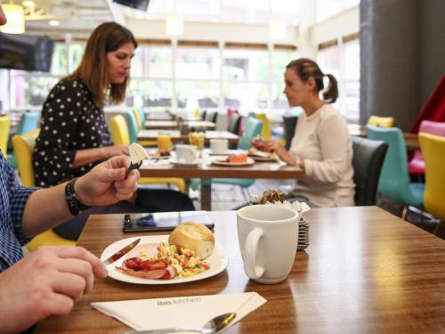 a group of people sitting at a table with a plate of food at Ibis Maringa in Maringá