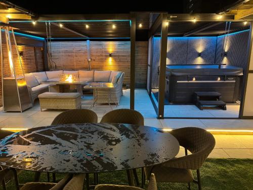 a patio with a table and a couch and a fireplace at 5 Bed Town House With Additional Luxury Hot Tub And Within City Centre And Sleeps Up To 11 With Sky And Netflix in Birmingham