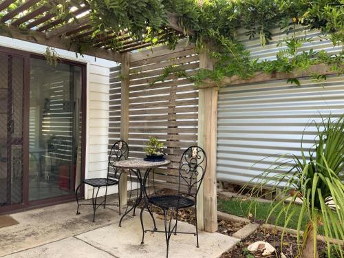 a patio with two chairs and a table in front of a garage at Jetty Rd Granny Flat in Normanville