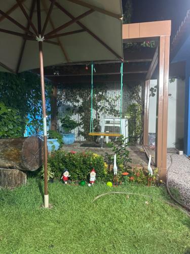 a garden with figurines in the grass with an umbrella at A casa do Breno in São José da Coroa Grande