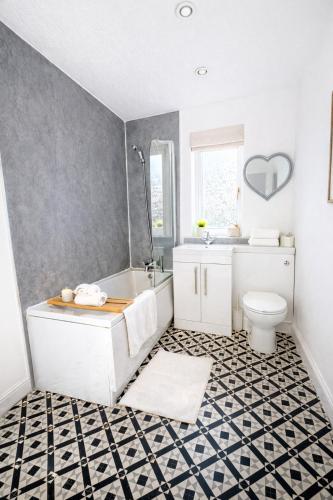 a bathroom with a tub and a sink and a toilet at Champflower House- Sleeps 7- Driveway Parking, Contractors, Fast Wifi and Smart TV in Milton Keynes