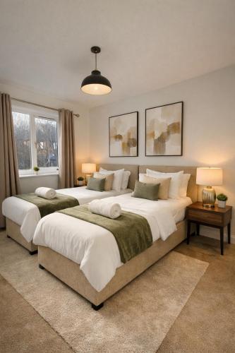 two beds in a large bedroom with two lamps at Champflower House- Sleeps 7- Driveway Parking, Contractors, Fast Wifi and Smart TV in Milton Keynes