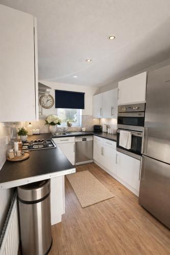 a kitchen with white cabinets and stainless steel appliances at Champflower House- Sleeps 7- Driveway Parking, Contractors, Fast Wifi and Smart TV in Milton Keynes
