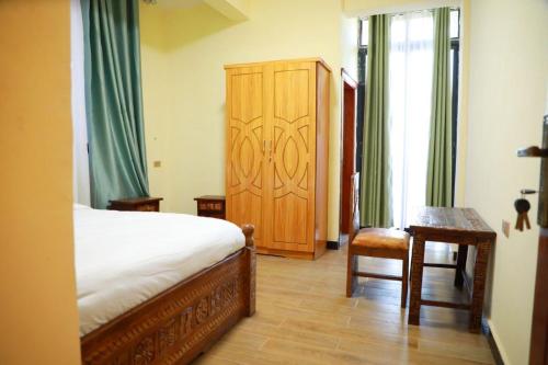 a bedroom with a bed and a wooden cabinet at Kings Land Hotel in Lalībela